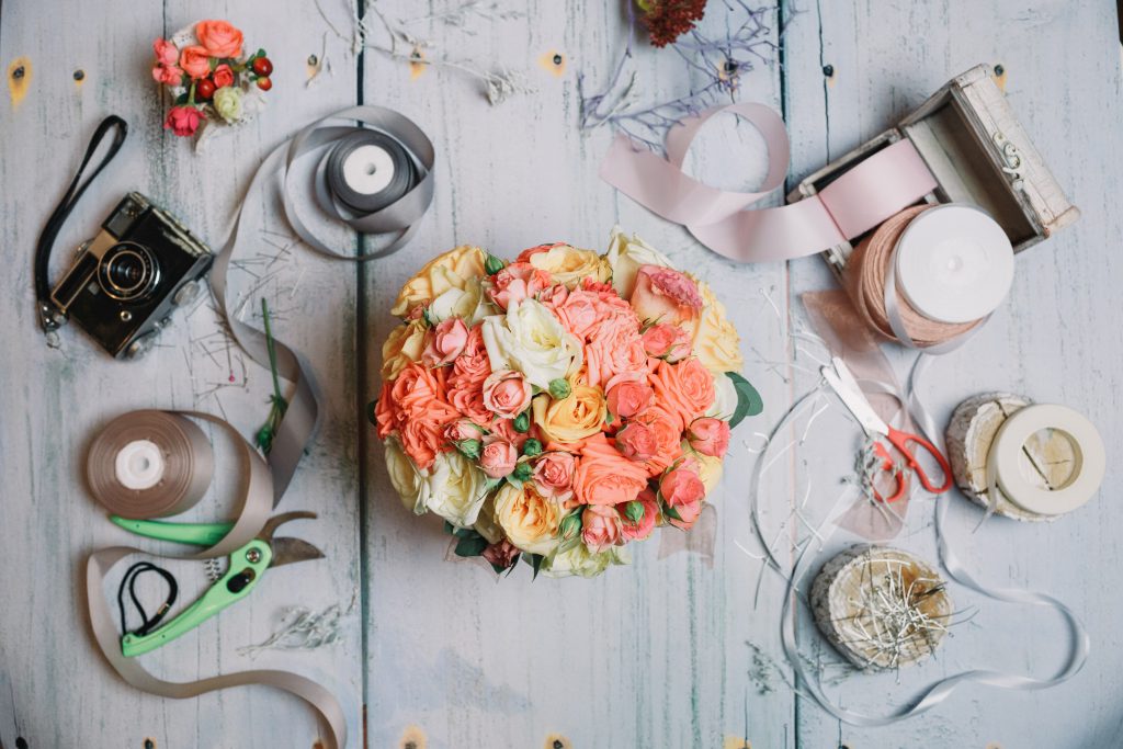 Flatlay of orange wedding bouquet and ribbons on working table